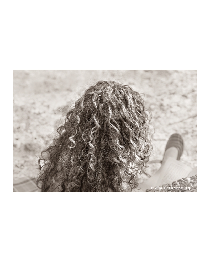 JBF125 Curly haired girl reading on the beach